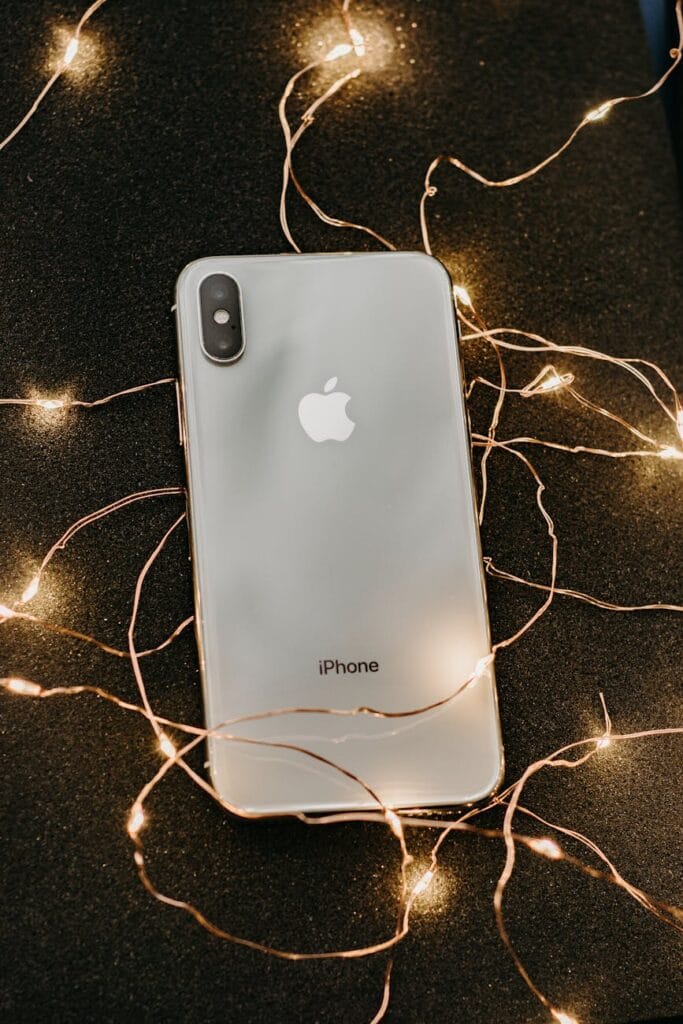 Miglior iPhone per qualità-prezzo nel 2025: quale scegliere? 2 miglior iphone A sleek smartphone lies on a glittering black surface adorned with warm string lights, showcasing modern technology.
